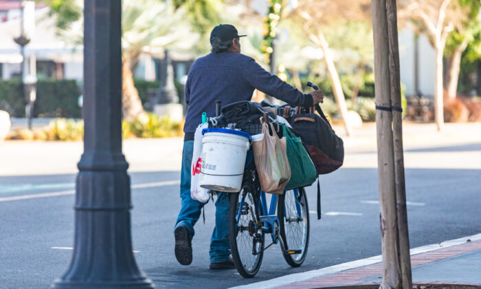 A homeless man walks with his bike and possessions in Santa Ana, Calif., on Dec. 17, 2020. (John Fredricks/The Epoch Times)