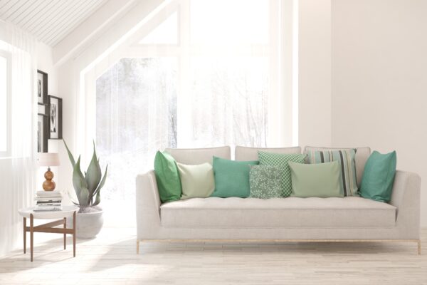A couch with green pillows in a sunny living room.