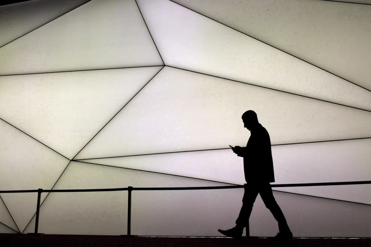 A man looks at his phone as he walks along the Samsung stand during the Mobile World Congress wireless show in Barcelona, Spain, on Feb. 27, 2017. (The Canadian Press/AP, Emilio Morenatti)