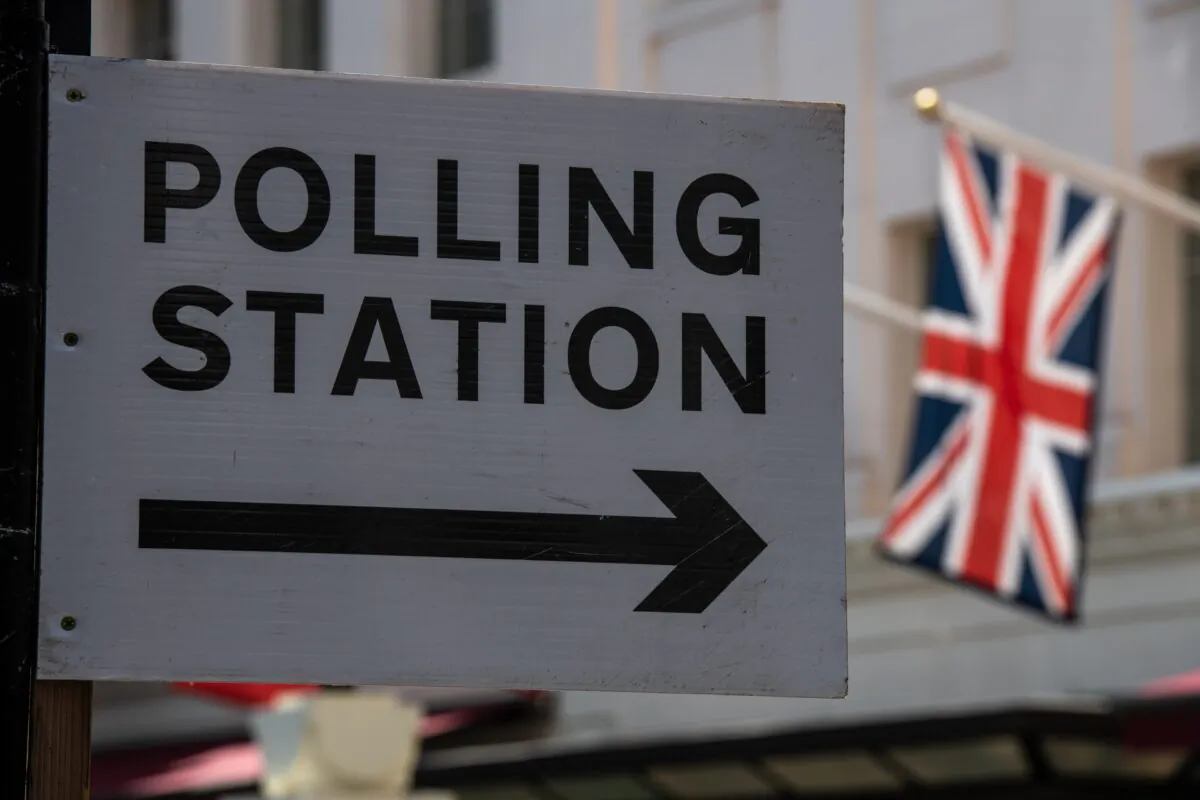 A Union Jack flag flies behind a sign pointing to a polling station in London, England, on May 5, 2022. (Chris J Ratcliffe/Getty Images)