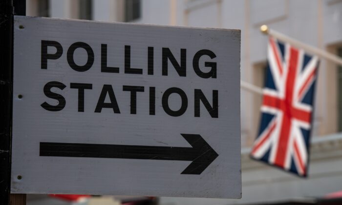 A Union Jack flag flies behind a sign pointing to a polling station in London, England, on May 5, 2022. (Chris J Ratcliffe/Getty Images)