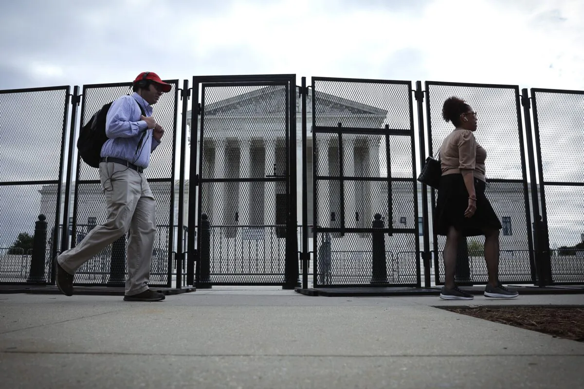People walk by fencing that was erected around the Supreme Court building in Washington on May 5, 2022. (Win McNamee/Getty Images)