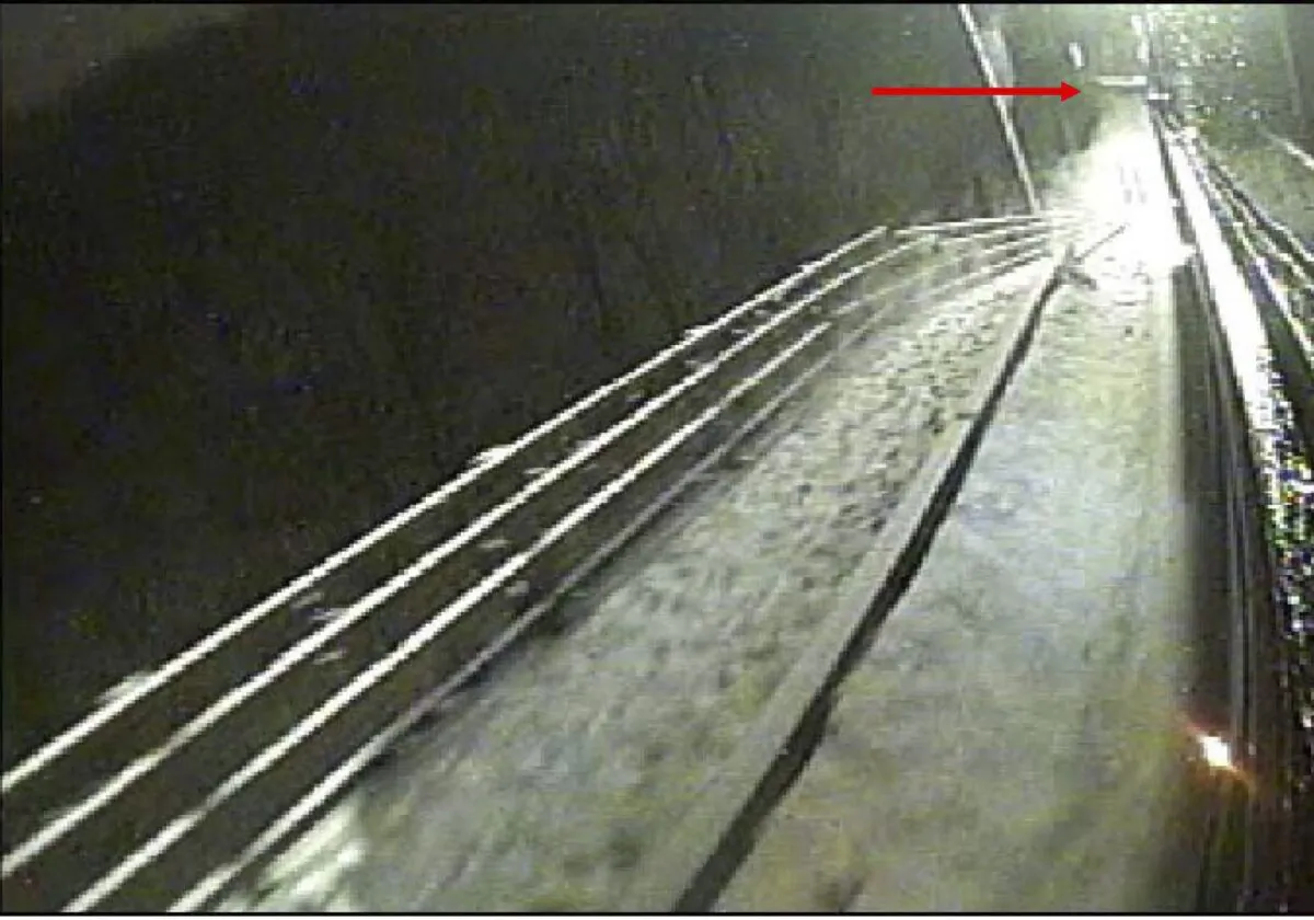 The National Transportation Safety Board (NTSB) says this image is from the curbside camera of the bus involved in the collapse of the Fern Hollow Bridge in Pittsburgh and shows that at nearly the same time, the west end of the bridge had already fallen off the west abutment (the red arrow points to the abutment). (National Transportation Safety Board via AP)