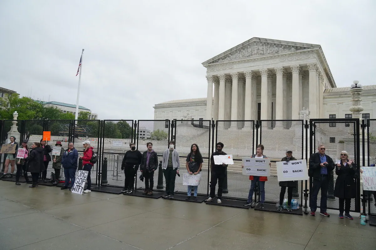 Pro-abortion protesters with signs stand in front of the U.S. Supreme Court in the rain on May 6, 2022 (Jackson Elliott/The Epoch Times)