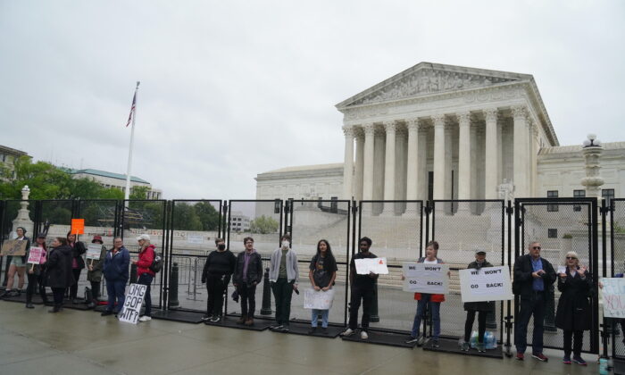 Pro-abortion protesters with signs stand in front of the U.S. Supreme Court in the rain on May 6, 2022 (Jackson Elliott/The Epoch Times)