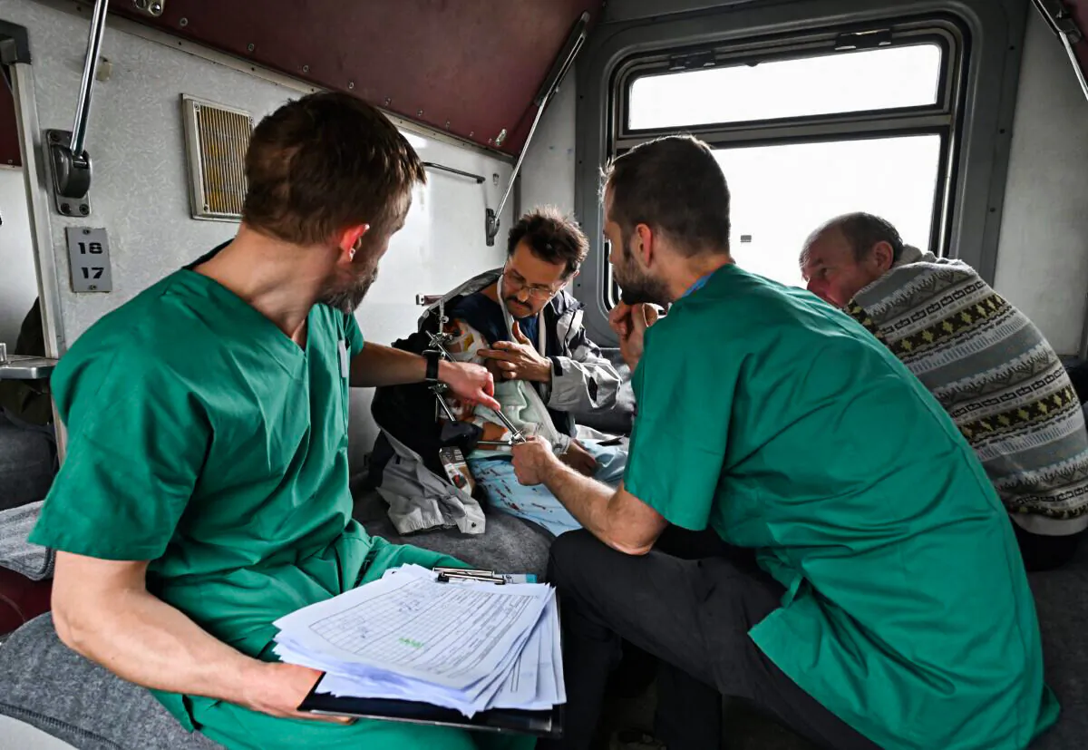 MSF doctors Stig Walravens (2nd R), 33, and Yaroslav (L), 39, care for Oleh, 58, a patient on a medical evacuation train on its way to the western Ukrainian city of Lviv on April 10, 2022. (Genya Savilov/AFP via Getty Images)