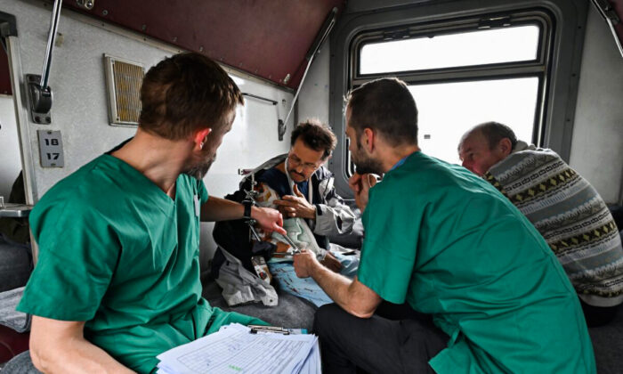 MSF doctors Stig Walravens (2nd R), 33, and Yaroslav (L), 39, care for Oleh, 58, a patient on a medical evacuation train on its way to the western Ukrainian city of Lviv on April 10, 2022. (Genya Savilov/AFP via Getty Images)