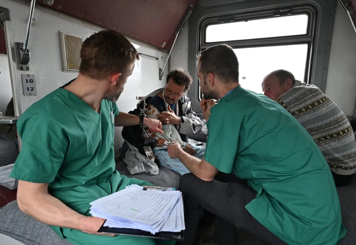 MSF doctors Stig Walravens (2nd R), 33, and Yaroslav (L), 39, care for Oleh, 58, a patient on a medical evacuation train on its way to the western Ukrainian city of Lviv on April 10, 2022. (Genya Savilov/AFP via Getty Images)