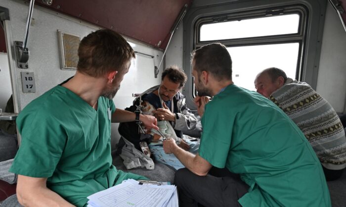2022 年 4 月 10 日，无国界医生 33 岁的 Stig Walravens（右二）和 39 岁的 Yaroslav（左）正在照顾 58 岁的 Oleh，他是乘坐医疗后送列车前往乌克兰西部城市利沃夫的列车。（根亚萨维洛夫/法新社通过盖蒂图片）