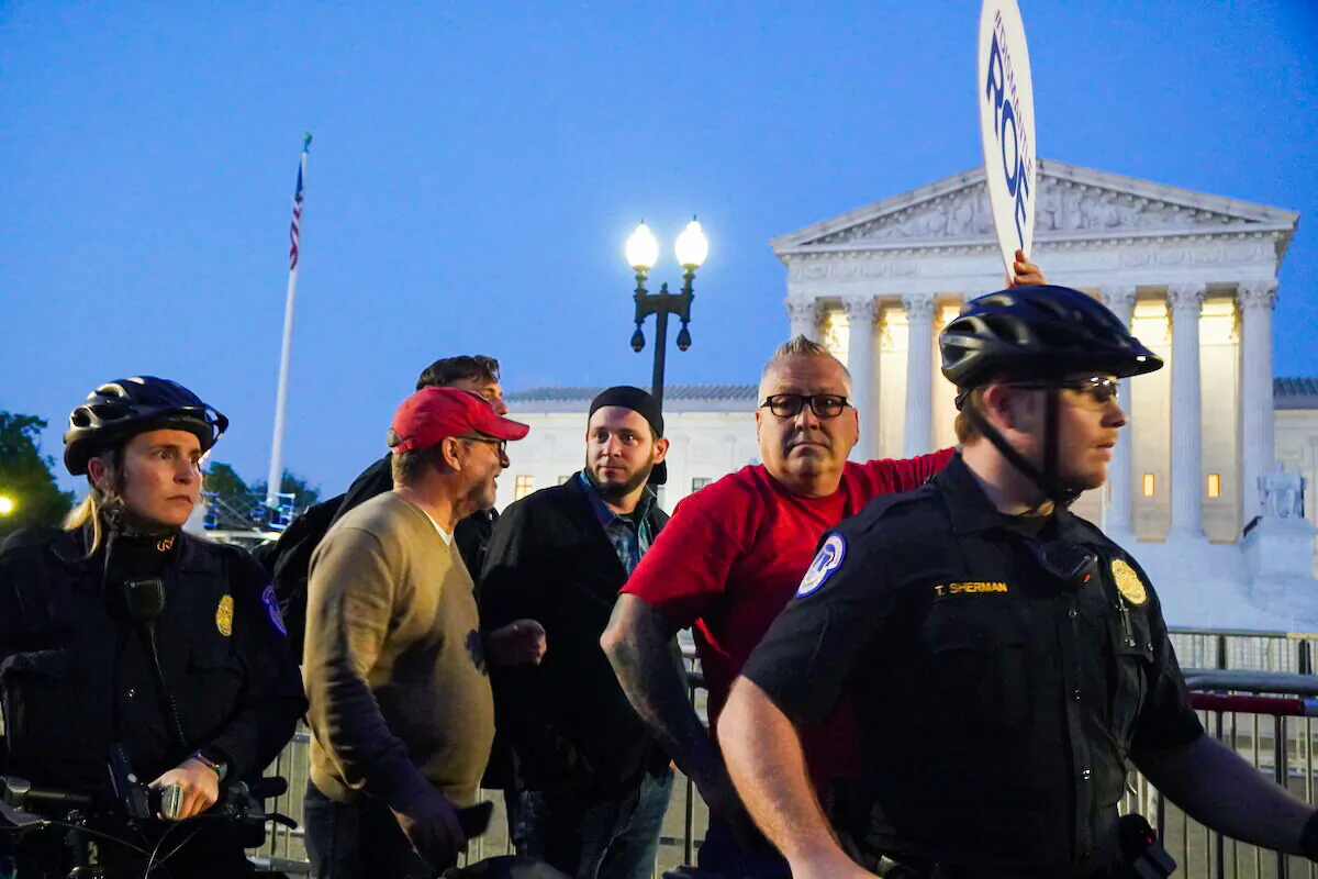 Rev. Patrick Mahoney (front left), A.J. Hurley (rear left), Bryan Kemper(right), and Pastor Mark Lee Dickson (center), stand in front of the Supreme Court while surrounded by police and protestors on May 4, 2022 (Jackson Elliott/The Epoch TImes).JPG