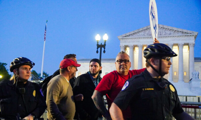 Rev. Patrick Mahoney (front left), A.J. Hurley (rear left), Bryan Kemper(right), and Pastor Mark Lee Dickson (center), stand in front of the Supreme Court while surrounded by police and protestors on May 4, 2022 (Jackson Elliott/The Epoch TImes).JPG