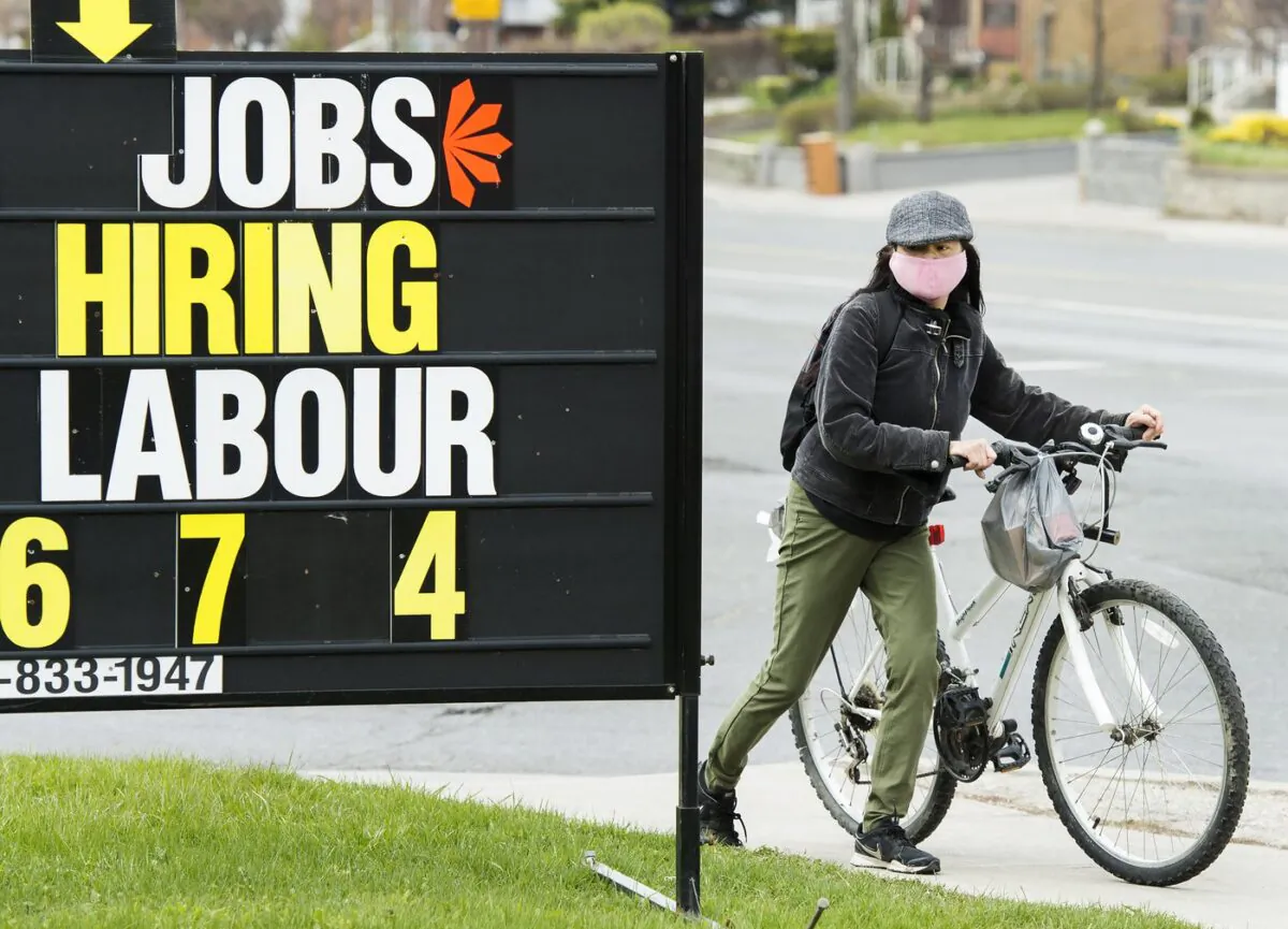 A woman checks out a jobs advertisement sign in Toronto on April 29, 2020. (The Canadian Press/Nathan Denette)