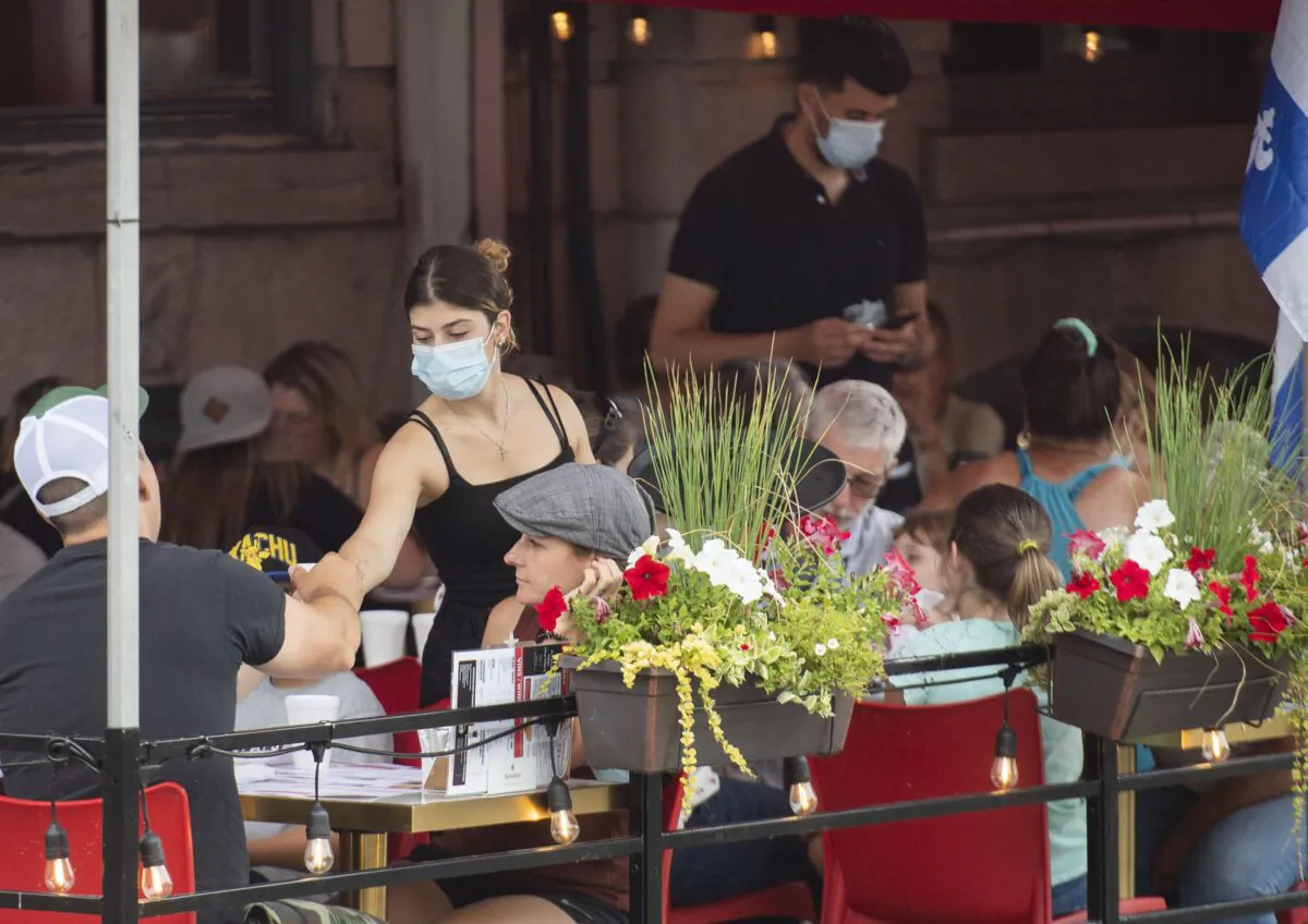 A server tends to customers at a restaurant in Old Montreal on July 18, 2021. The food service industry is just one of multiple sectors facing dire labour shortages. (The Canadian Press/Graham Hughes)