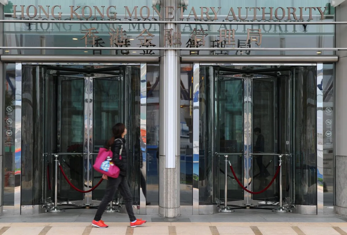 A woman walks beneath signage for the Hong Kong Monetary Authority, Hong Kong, on Dec. 20, 2012. (Dale De La Rey/AFP via Getty Images)