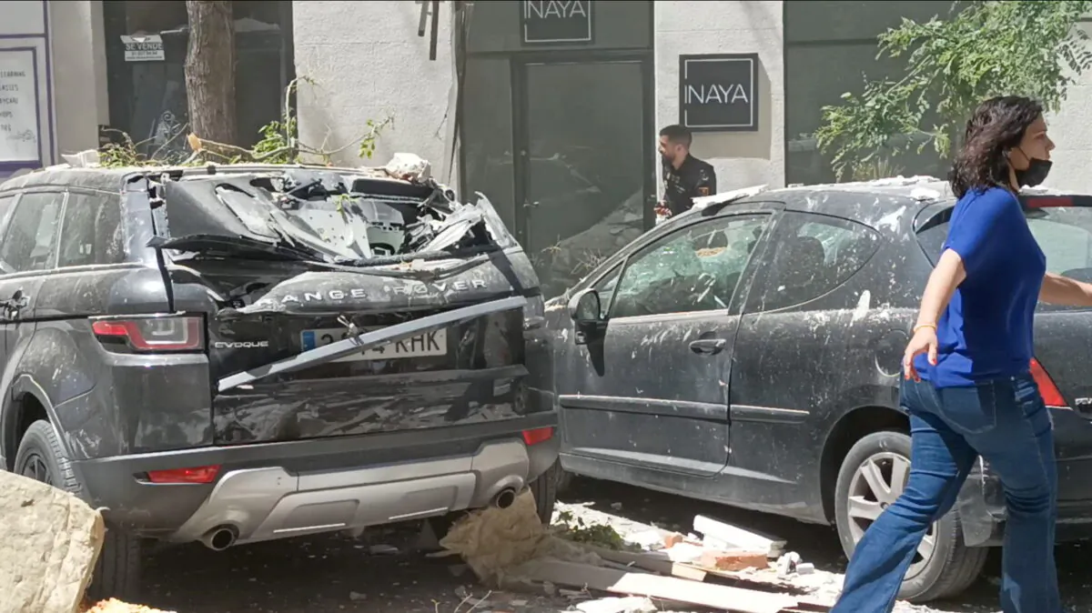 A woman walks past debris and damaged vehicles, following a suspected gas explosion in Madrid, Spain, on May 6, 2022, in this screengrab obtained from a social media video. (Victor Manuel Arellano/Screenshot via Reuters)