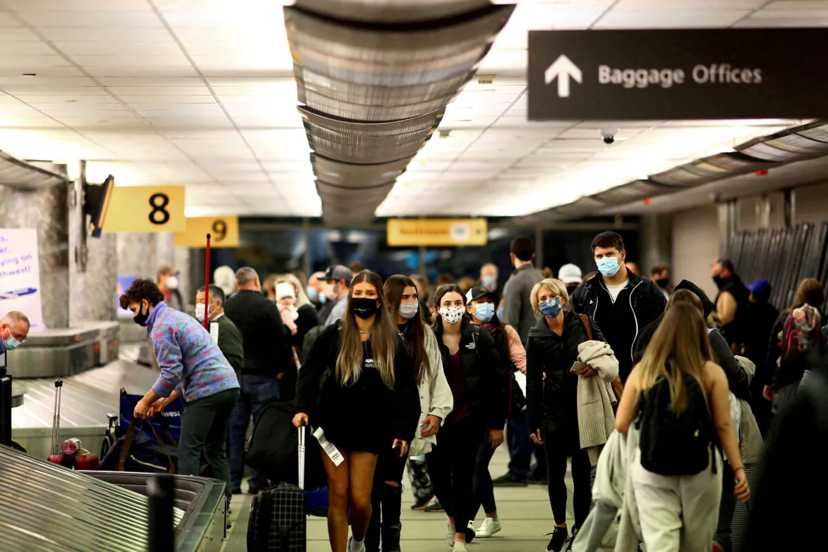 Travelers wearing protective reclaim their luggage at the airport in Denver on Nov. 24, 2020. (Kevin Mohatt/Reuters)