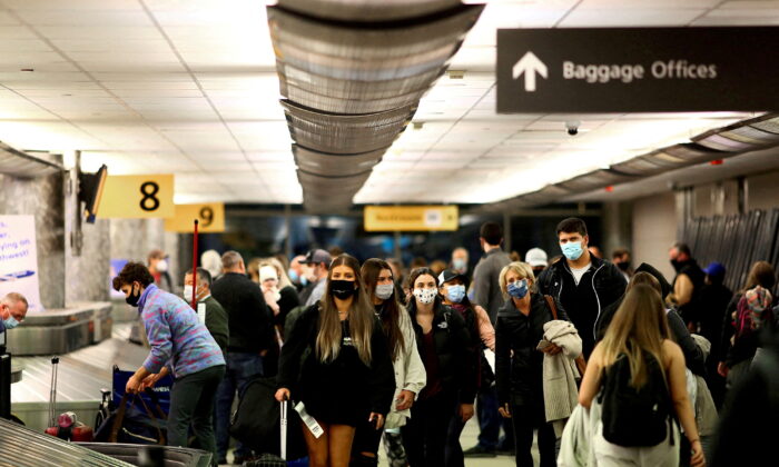 Travelers wearing protective reclaim their luggage at the airport in Denver on Nov. 24, 2020. (Kevin Mohatt/Reuters)