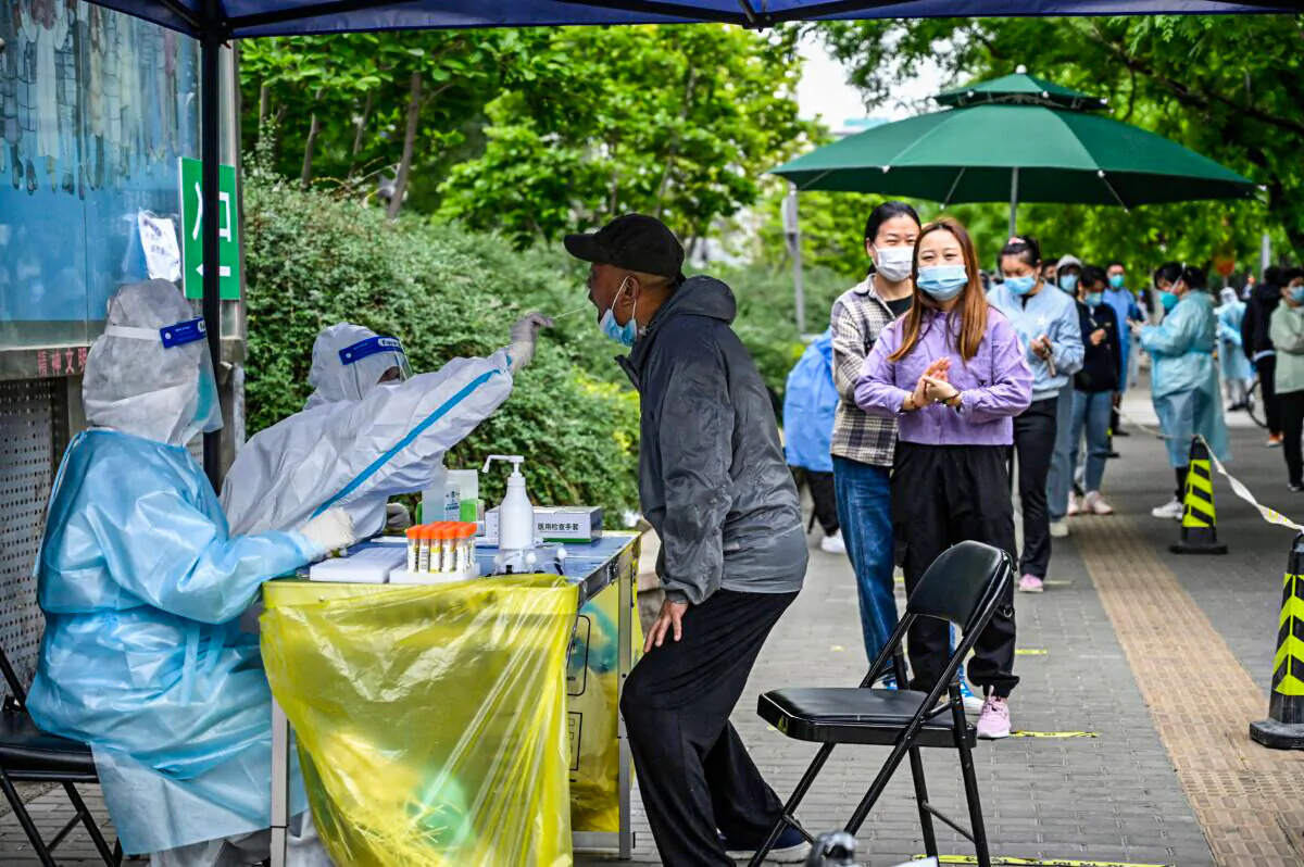 A health worker takes a swab sample from a man to be tested for COVID-19 coronavirus at a makeshift testing site along a street in Beijing on May 7, 2022. (Jade Gao/AFP via Getty Images)