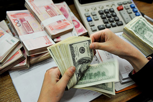 The Chinese Communist Party's draconian COVID measures have accelerated the outflow of wealthy Chinese residents and their capitals. This photo shows a bank teller counting stacks of US dollars and Chinese 100-yuan notes at a bank in Hefei, Anhui province, China. (STR/AFP/Getty Images)