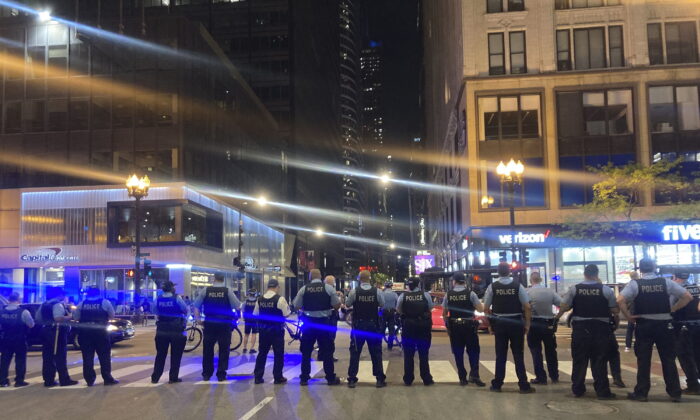 Chicago police block traffic near State and Monroe streets after crowds of young people flooded the Loop after a fatal shooting in Millennial Park in Chicago, on May 14, 2022. (Tina Sfondeles/Chicago Sun-Times via AP)