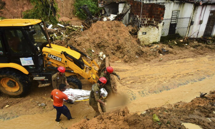 Firefighters carry a body recovered from a landslide triggered by heavy rain in the Jardim Monte Verde neighborhood of Recife in Pernambuco state, Brazil, on May 29, 2022. (Joao Carlos Mazella/AP Photo)