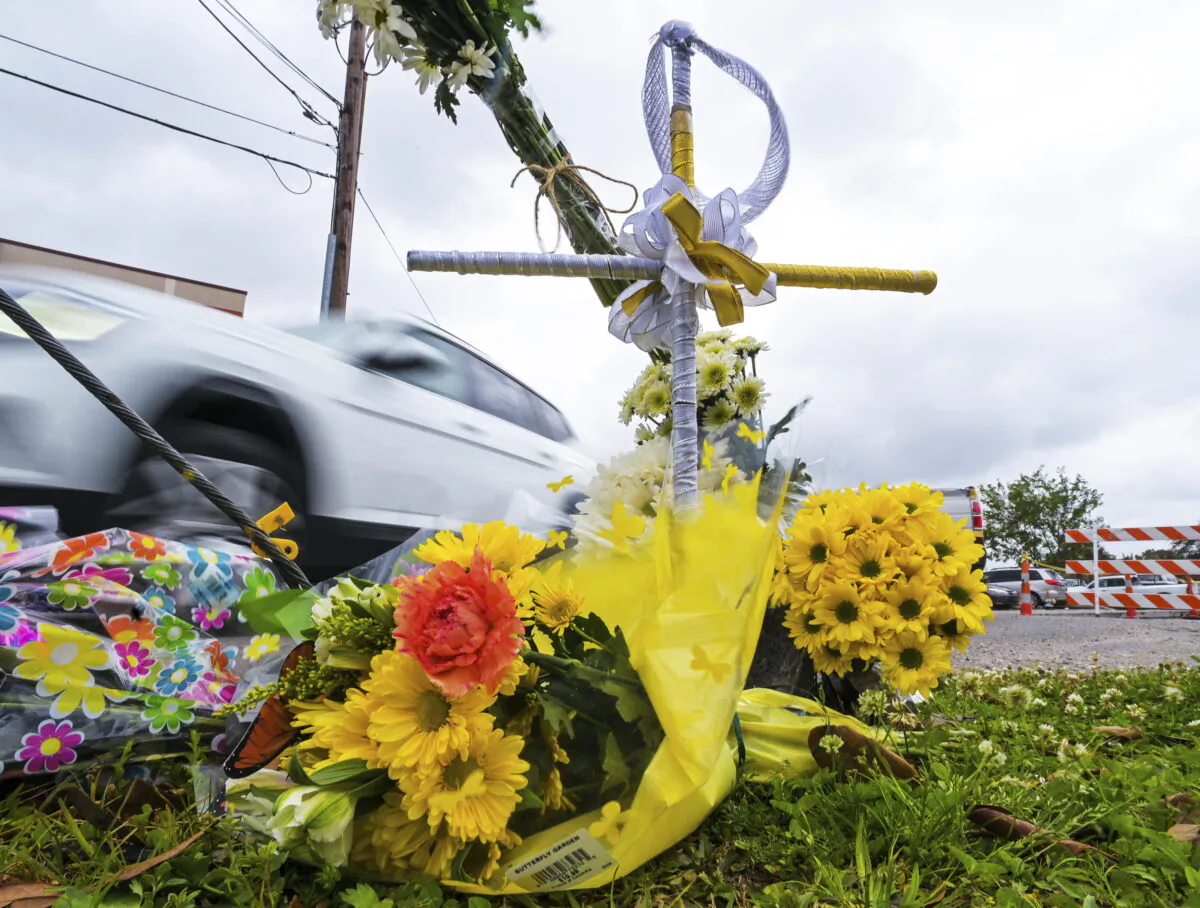 A collection of flowers and a cross with a halo at the location where the body of Linda Frickey was recovered after she was carjacked and dragged to her death a day earlier on N. Pierce Street in New Orleans, on March 22, 2022. (Max Becherer/The Times-Picayune/The New Orleans Advocate via AP)