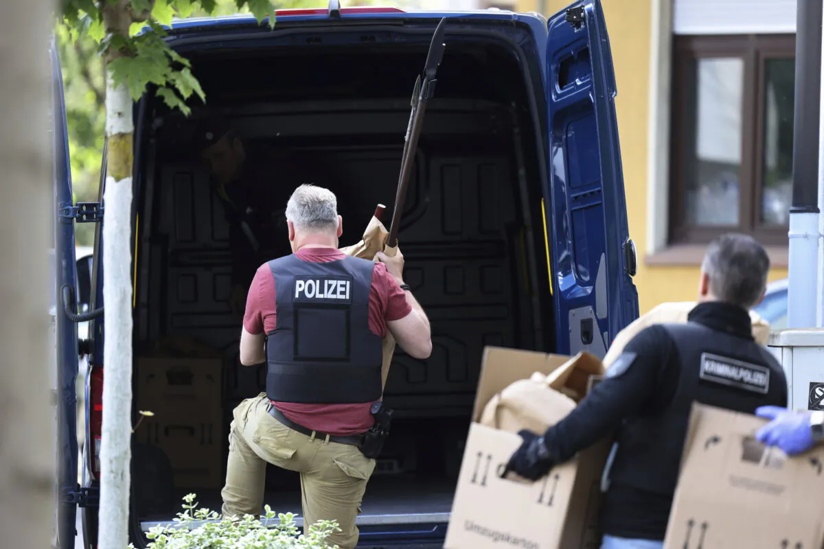 Police officers carry objects, including several stabbing weapons and spears, from the suspect's home in Essen, Germany, on May 12, 2022. (David Young/dpa via AP)