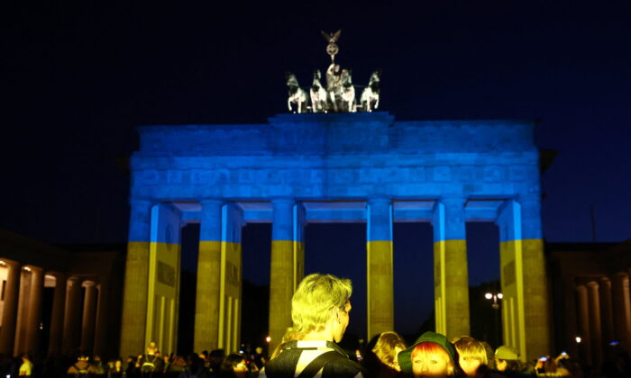 2022 年 5 月 9 日，在德国柏林，俄罗斯袭击乌克兰期间，人们参观了被乌克兰国旗颜色照亮的勃兰登堡门。（路透社/Lisi Niesner/档案照片）