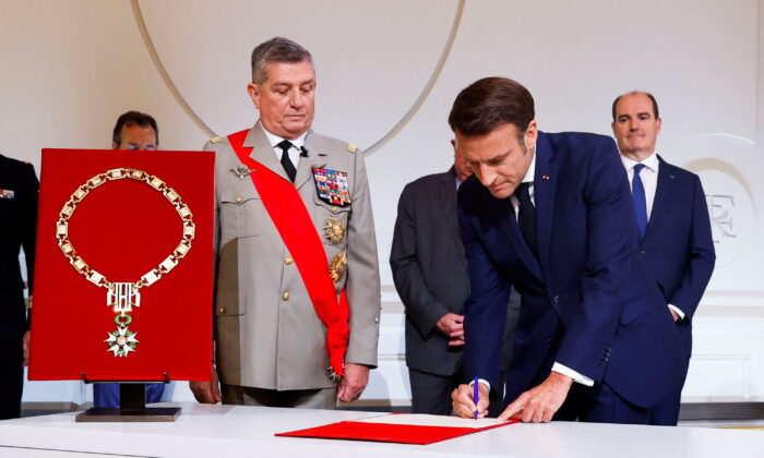 France's Military Chief of Staff to the presidency Benoit Puga stands next to French President Emmanuel Macron (R) signing a document as he is sworn-in for a second term as president after his reelection, during a ceremony at the Elysee Palace in Paris on May 7, 2022. (Gonzalo Fuentes/Pool via Reuters)