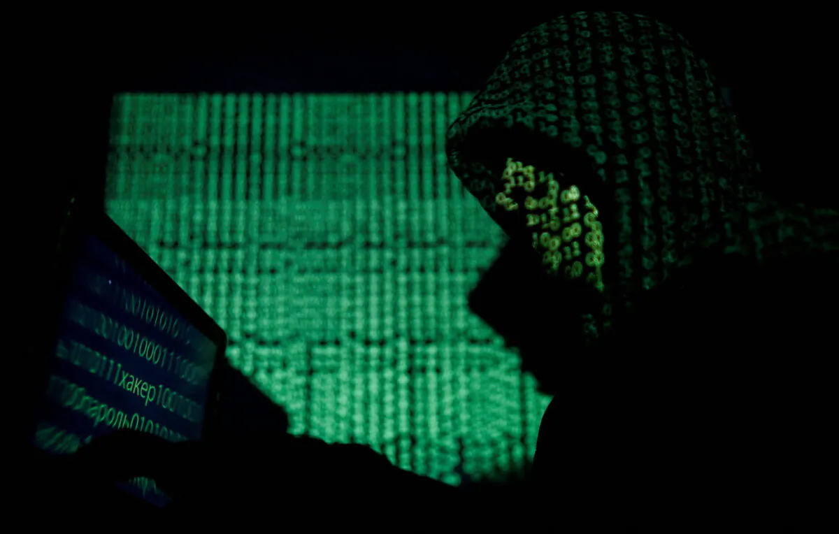 A hooded man holds a laptop computer as cyber code is projected on him in this illustration picture taken on May 13, 2017. (Kacper Pempel/Illustration/Reuters, File Photo0