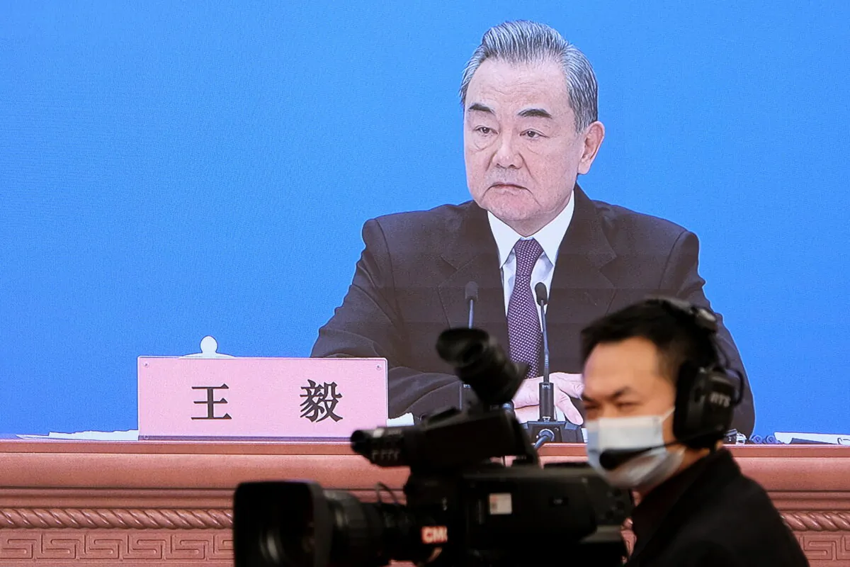 FILE PHOTO: Chinese State Councilor and Foreign Minister Wang Yi is seen on a screen as he attends a news conference via video link on the sidelines of the National People's Congress (NPC), in Beijing, China March 7, 2022. REUTERS/Ryan Woo