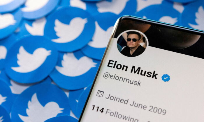 Elon Musk's Twitter profile on a smartphone placed on printed Twitter logos on April 28, 2022. (Dado Ruvic/Reuters)