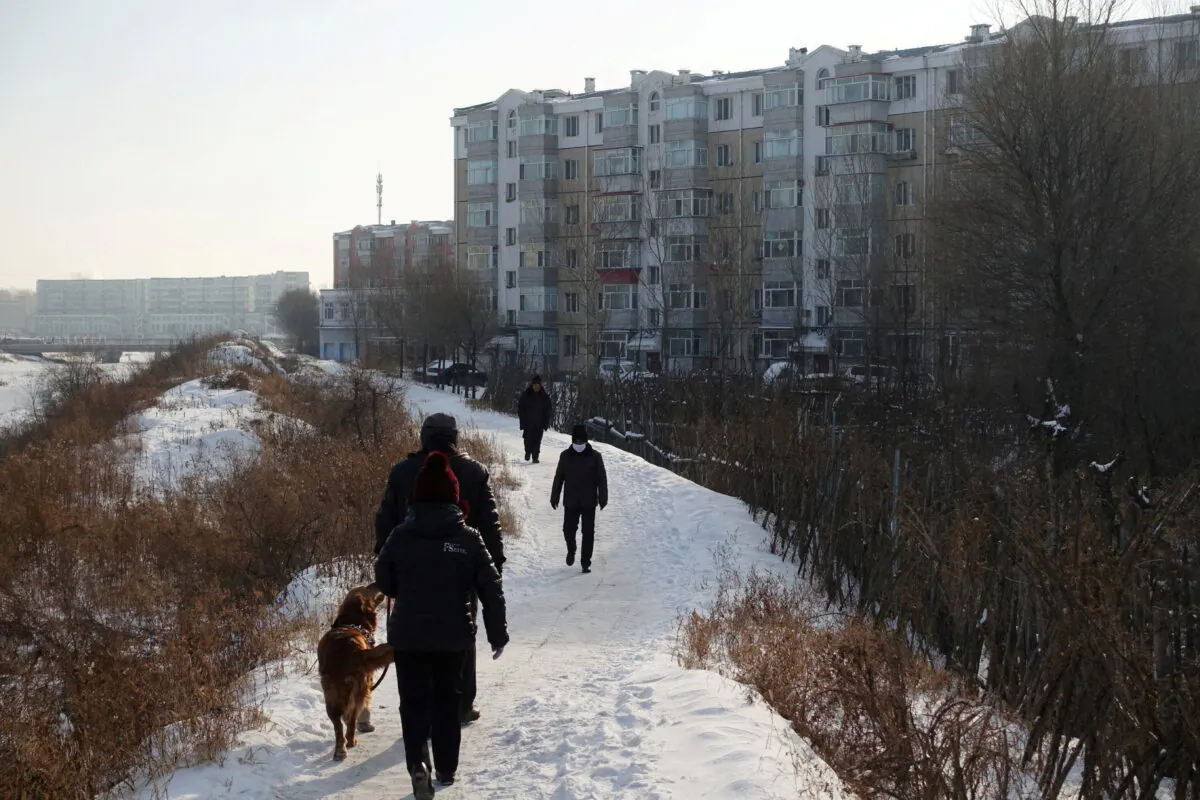 People walk next to residential buildings in the coal city of Hegang, Heilongjiang Province, China on Jan. 2, 2020. (Ryan Woo/Reuters)