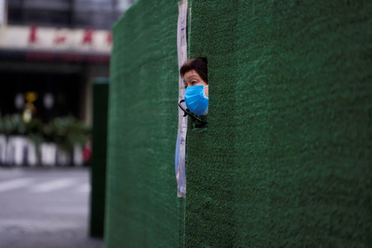 A resident looks out through a gap in the barrier at a residential area during lockdown, amid the coronavirus disease (COVID-19) pandemic, in Shanghai, China, on May 6, 2022. (Aly Song/Reuters)