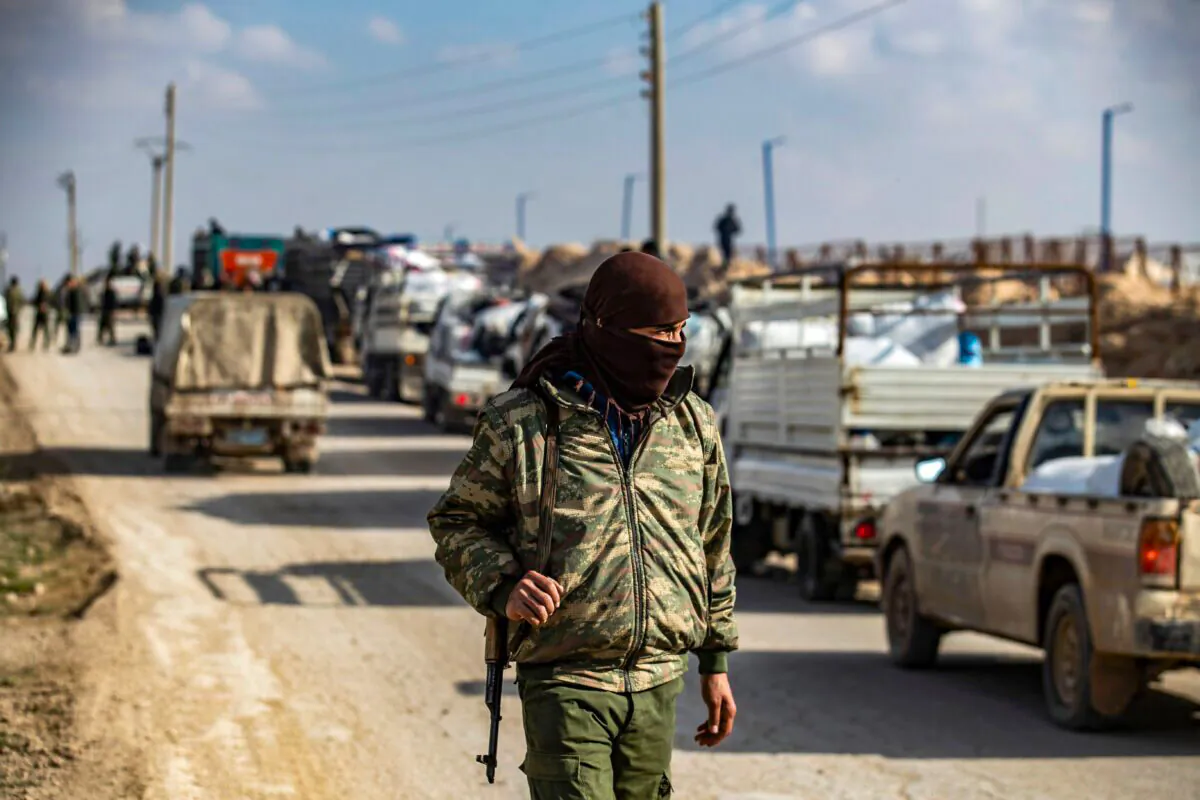 An internal security patrol member stands in front of a convoy of trucks transporting Syrian women and children suspected of being related to the ISIS terrorist group, at the Kurdish-run al-Hol camp, in the al-Hasakeh governorate in northeastern Syria, on Dec. 21, 2020. (Delil Souleiman/AFP via Getty Images)