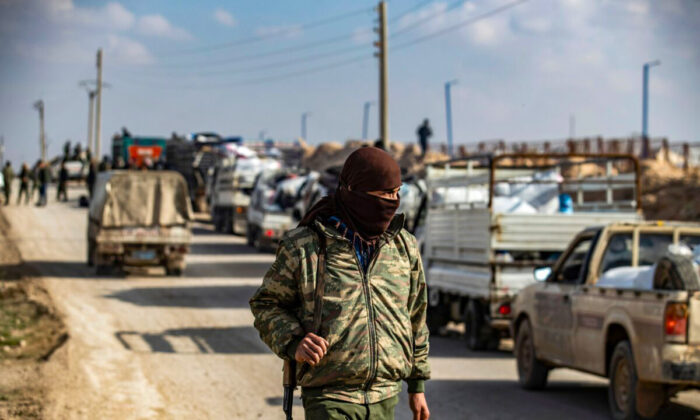 An internal security patrol member stands in front of a convoy of trucks transporting Syrian women and children suspected of being related to the ISIS terrorist group, at the Kurdish-run al-Hol camp, in the al-Hasakeh governorate in northeastern Syria, on Dec. 21, 2020. (Delil Souleiman/AFP via Getty Images)