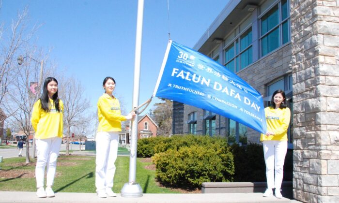 Falun Dafa adherents raise a flag in celebration of the 30th anniversary of the spread of the spiritual practice, in the City of Milton, Ont. on April 29, 2022. (Arek Rusek/The Epoch Times)