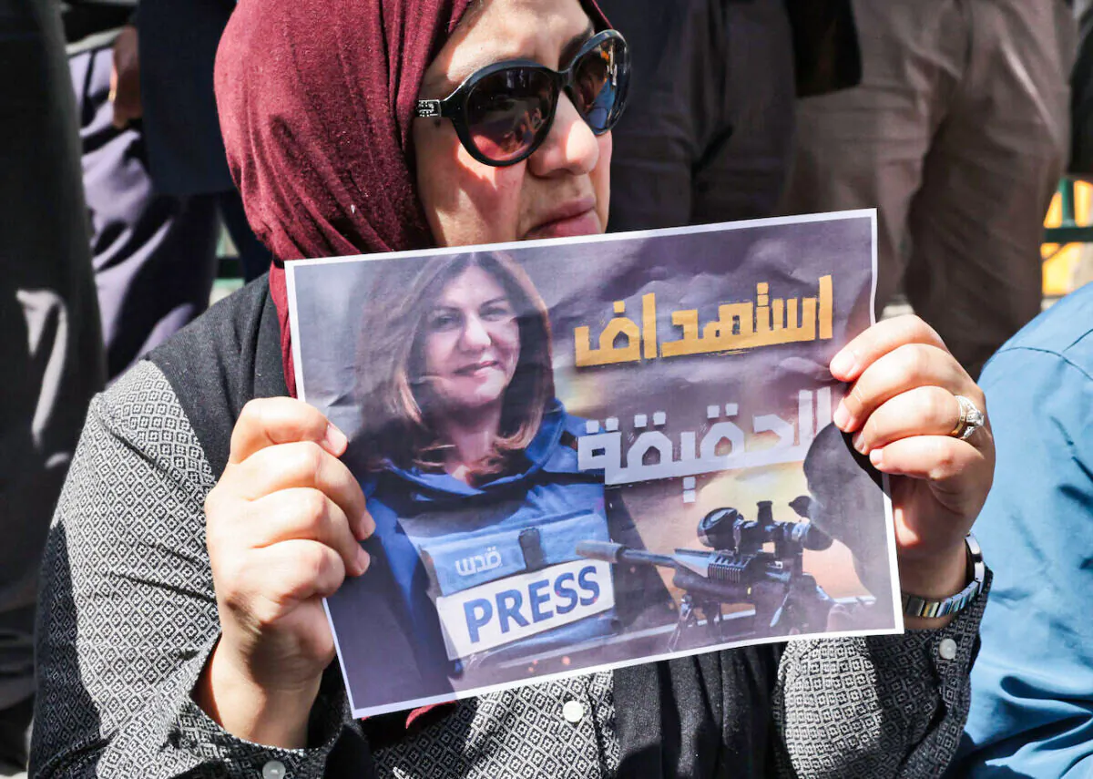 Palestinians hold posters displaying veteran Al Jazeera journalist Shireen Abu Akleh, who was fatally shot as she covered a raid on the West Bank's Jenin refugee camp in the West Bank city of Hebron, on May 11, 2022. (Hazem Bader/AFP via Getty Images)