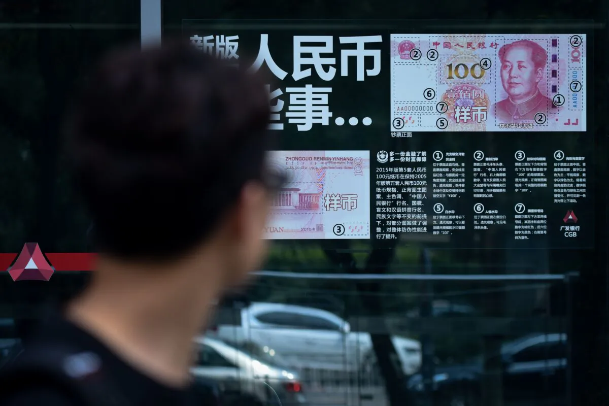 A man looks at information posted on a bank door showing how to distinguish counterfeit banknotes in Beijing on July 20, 2018. (Wang Zhao/AFP via Getty Images)