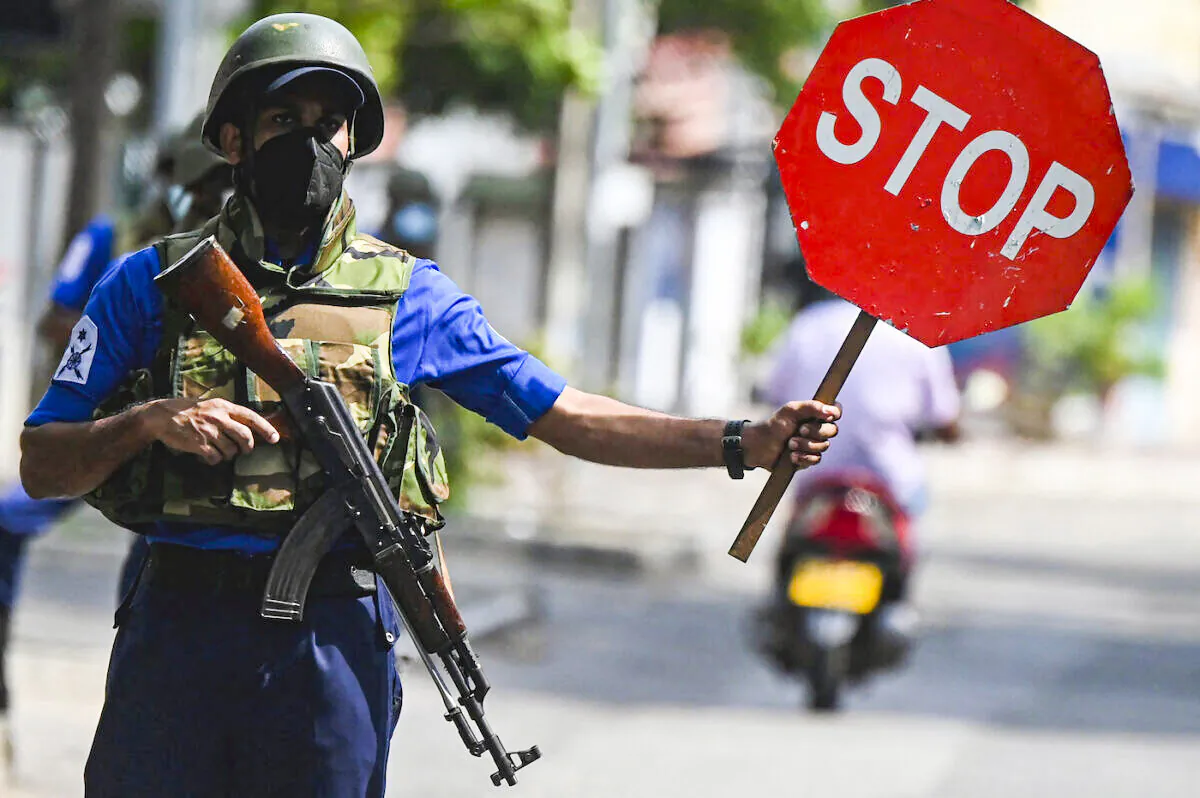 A navy soldier holds a stop sign at a road checkpoint in Colombo on May 11, 2022. (Ishara S. Kodikara/AFP via Getty Images)