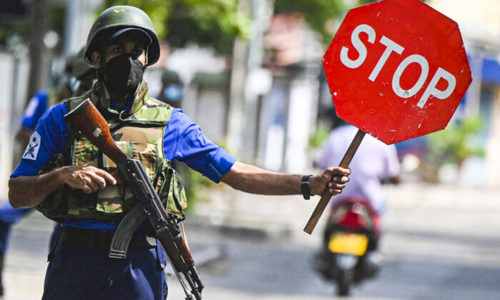 A navy soldier holds a stop sign at a road checkpoint in Colombo on May 11, 2022. (Ishara S. Kodikara/AFP via Getty Images)