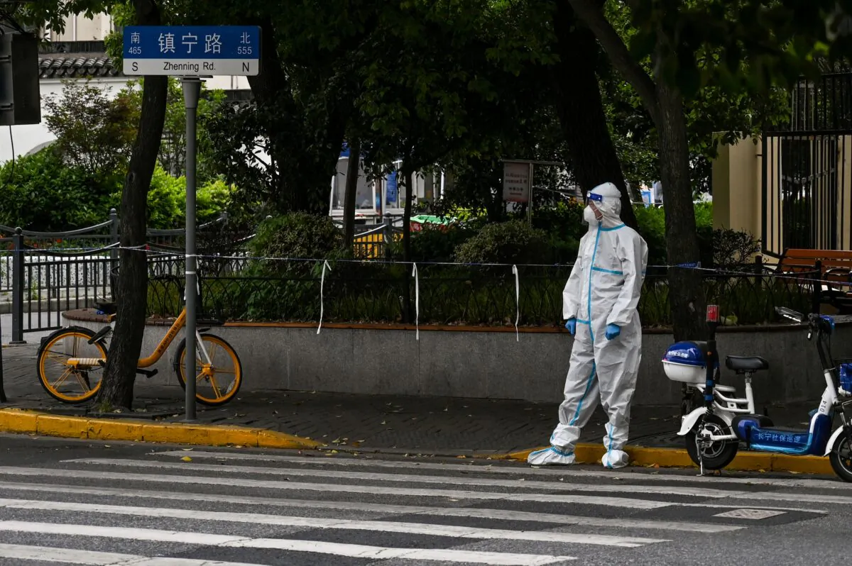 A worker standing on a street during a Covid-19 coronavirus lockdown in the Jing'an district in Shanghai on May 10, 2022. (Hector Retamal/AFP via Getty Images)