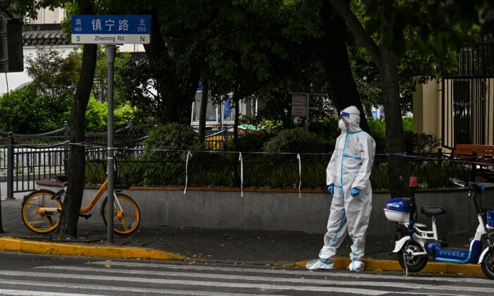 A worker standing on a street during a Covid-19 coronavirus lockdown in the Jing'an district in Shanghai on May 10, 2022. (Hector Retamal/AFP via Getty Images)