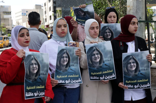 Palestinians hold posters displaying veteran Al Jazeera journalist Shireen Abu Akleh