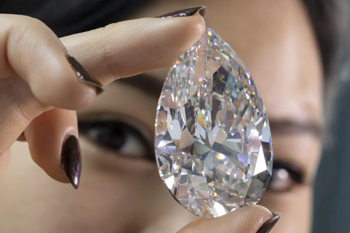 A Christie's employee holds "The Rock" a white diamond of 228,31 carats which is the largest white diamond ever seen throughout auction market history, during a preview at Christie's, in Geneva, on May 6, 2022. (Salvatore Di Nolfi/Keystone via AP)