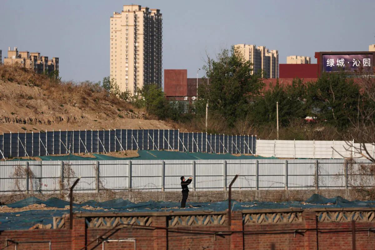 A man walks at a construction site near residential buildings in Beijing on April 14, 2022. (Tingshu Wang/Reuters)