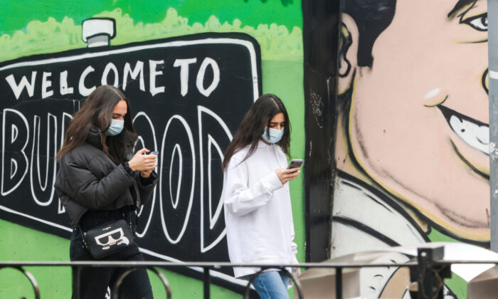 Two girls in masks walk past a "welcome to Burwood" mural in Sydney, Australia, on July 24, 2021. (Jenny Evans/Getty Images)