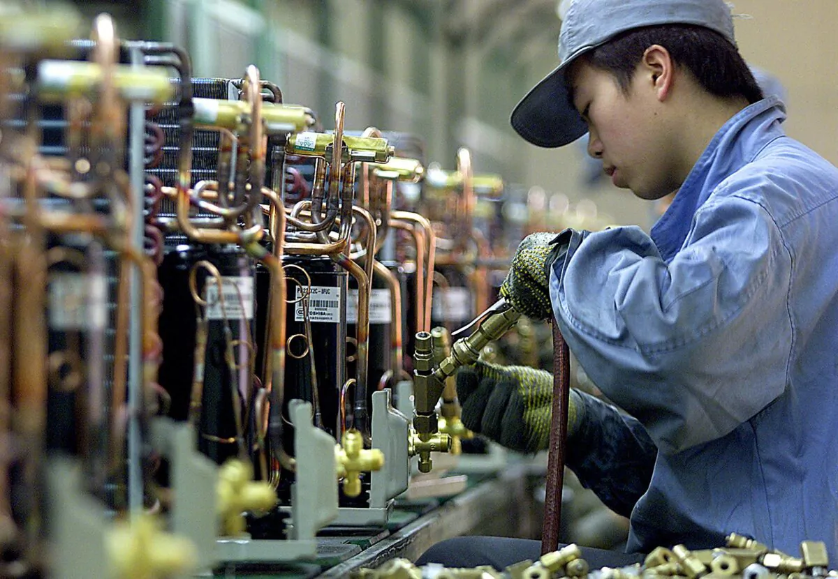 A Chinese worker fixes compressors along an air conditioners production line at the Japanese Hitachi Household Electrical Appliances Company in Shanghai, in March 2003. (Liu Jin/AFP via Getty Images)