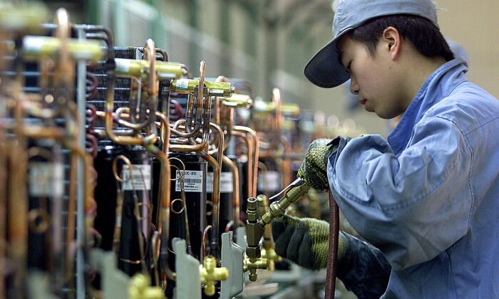 A Chinese worker fixes compressors on an air conditioner production line at the Japanese Hitachi Household Electrical Appliances Company in Shanghai, March 13, 2003. (Liu Jin/AFP via Getty Images)