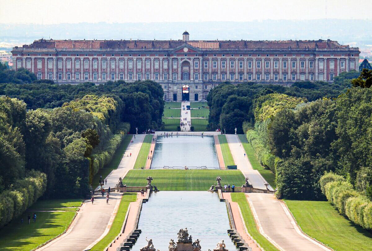 Standing five stories tall and 810 feet wide, the Royal Palace of Caserta is the largest palace by volume in the world. This view of the back side of the palace only hints at the incredible two-mile-long promenade and waterway that stretch vastly across the Italian landscape like a man-made river adorned by impressive fountains and sculptures that are framed by natural forests. (Carlo Pelagalli/CC BY-SA 3.0)